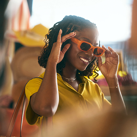 woman putting on orange sunglasses and smiling