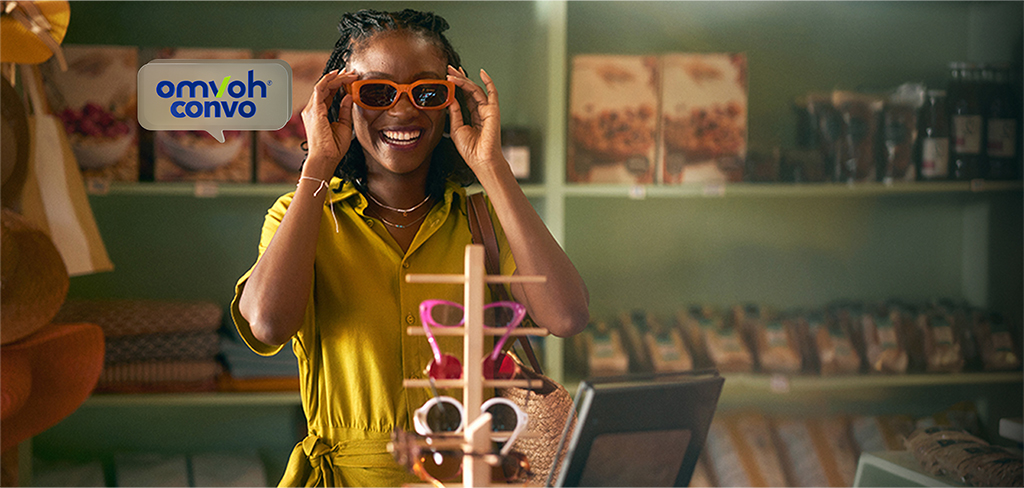 Mujer con vestido amarillo probándose gafas anaranjadas en una tienda.