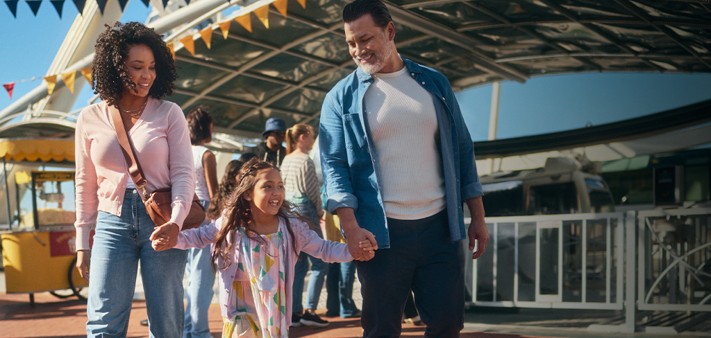 Madre y padre sosteniendo la mano de su hija saliendo de la rueda de la fortuna.