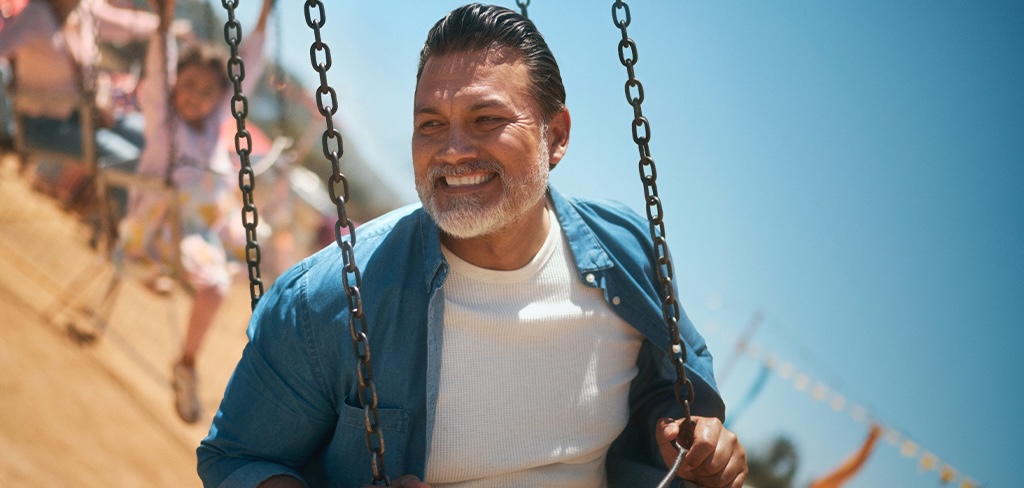 Hombre en una silla voladora de feria, sonriendo